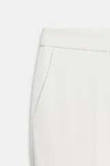 Pantalón de tiro bajo color blanco, con pernera recta y bolsillos delanteros. Cuenta con cierre frontal con cremallera, botón interior y gancho.
