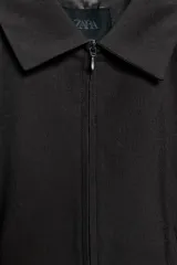 Cazadora entallada de color gris oscuro, con cuello solapa, manga larga y cierre frontal con cremallera de doble cursor. Presenta costuras marcadas y forro interior.