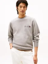 Buzo de cuello redondo Tommy Hilfiger en color gris melange, con diseño de logo y escudo bordados en el pecho. Presenta puños y ruedo acanalados.