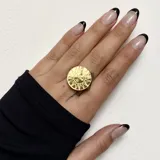 Anillo dorado con forma circular y diseño de sol con rostro.