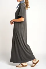 Vestido largo gris oscuro de algodón, con cuello redondo y mangas cortas. Presenta un tajo lateral alto.