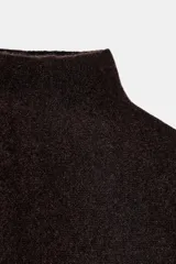 Capa de punto con cuello subido, diseño holgado y caída fluida.