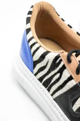 Zapatillas acordonadas con estampado de cebra, detalles en cuero negro y azul, y suela de plataforma blanca.
