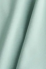 Top entallado de punto roma color verde menta, con diseño sin mangas de hombros cubiertos, cuello alto y corte peplum con vuelo en la parte inferior.