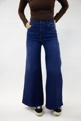 Pantalón jean de tiro alto y corte campana en color azul medio, con bolsillos delanteros y traseros, y cierre frontal con botón y cremallera.