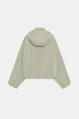 Cazadora de cuello subido con capucha ajustable, manga larga con puños elásticos y bajo elástico. Cuenta con bolsillos delanteros y cierre frontal con cremallera oculta y botones a presión.