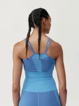 Top deportivo color gris con textura acanalada, tirantes finos y logo en el frente.