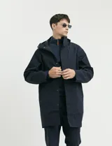 Gabardina con capucha de corte recto y largo medio. Cuenta con cierre frontal engomado, cartera con botones a presión, bolsillos laterales y tejido repelente al agua y al viento.