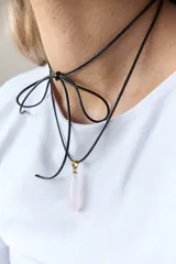 Gargantilla de cuero negro con dije de piedra blanca en forma de lágrima con engarce dorado.