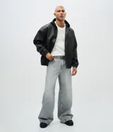 Pantalón de jean color gris claro con efecto desteñido, de corte muy ancho y holgado estilo baggy, tiro medio y bolsillos funcionales.