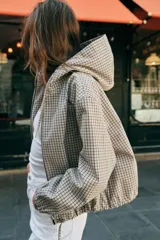 Cazadora con capucha ajustable, manga larga con puños elásticos, bolsillos delanteros y bajo ajustable con cordones. Cierre frontal con cremallera y diseño estampado a cuadros.