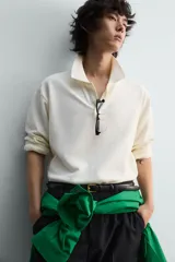 Polo de manga larga color rojo, confeccionado en tejido de algodón con estructura piqué, cuello solapa y cierre frontal de botonadura. Presenta aberturas laterales en el bajo.