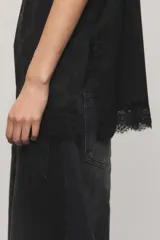 Top negro de satén jacquard, con escote en V de estilo lencero decorado con puntilla delicada al igual que el ruedo, breteles finos regulables y aberturas laterales.