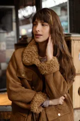 Campera de efecto gamuza color tostado con interior de corderito sintético. Presenta cierre frontal, bolsillos delanteros con solapa, cintura ajustable con cordón y puños con detalle de corderito.