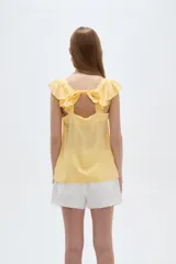 Musculosa amarilla de viscosa, con cuello en V y breteles anchos decorados con volados. Presenta un corte holgado.