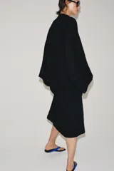 Vestido túnica largo negro de corte midi con mezcla de viscosa y lino, escote en V y mangas largas evasé. Presenta cierre frontal con alamares decorativos.