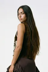 Chaleco negro de terciopelo con bordados florales en blanco y plateado, escote en V pronunciado y ribete plateado.