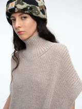 Chaleco tipo poncho de tejido de punto color tostado, con cuello polera y diseño holgado con laterales abiertos.