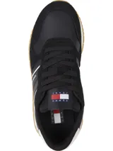 Zapatillas Tommy Jeans negras con detalles en blanco y suela color caramelo. Presentan paneles de cuero y gamuza, cordones negros y logo de la marca en el lateral.