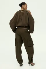 Pantalón cargo de sarga color verde militar, con tiro alto, cierre frontal con botón y corte holgado en las piernas estilo barrel. Cuenta con bolsillos laterales, bolsillos de fuelle con solapa en los muslos y trabillas abotonadas en los tobillos.