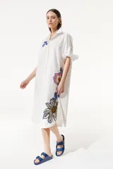 Túnica larga blanca abotonada con estampas de flores en tonos azules y rosados. De calce holgado, cuenta con manga tres cuartos y tablón en la espalda.