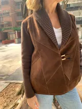 Chaqueta marrón de gamuza y lana tejida, con cuello tejido y cierre frontal con hebilla dorada.