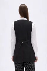 Chaleco largo de corte sastrero en color negro, con escote en V, cierre frontal de botones y bolsillos laterales simulados.