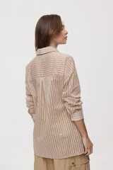 Camisa de rayas de calce relajado, confeccionada en tejido liviano y semitransparente, con cuello clásico, cierre frontal con botones, mangas largas con puños y hombros caídos.