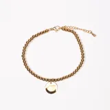 Pulsera dorada con cuentas redondas y dije circular.