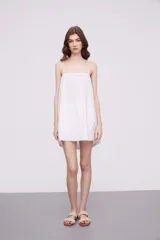 Vestido corto color marfil con breteles finos, escote recto y detalle de puntilla en los laterales y ruedo.