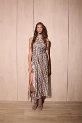 Vestido largo con estampado de piel de serpiente en tonos marrones y beige. Presenta un escote halter con drapeado en el busto y una abertura lateral alta en la falda.
