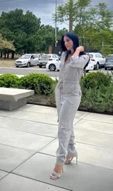 Mono largo gris con textura arrugada, cuello camisero, cierre frontal, bolsillos con solapa en el pecho y bolsillos cargo en las piernas. Incluye cordón ajustable en la cintura y mangas 3/4 con botón.