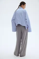 Pantalón sastrero gris de tiro alto, corte amplio y recto, con pinzas frontales y raya marcada en ambas piernas.