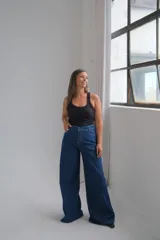 Jean de corte recto y tiro alto, confeccionado en denim azul clásico con costuras en hilo blanco a contraste. Presenta cierre frontal con botón metálico y bolsillos laterales.