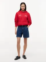 Buzo con capucha de Tommy Hilfiger en colaboración con Cadillac Formula 1 Team. Confeccionado en algodón, presenta un diseño de color rojo con bolsillo tipo canguro, puños y bajo acanalados. Incluye bordados en el pecho con banderas cruzadas y el logo de la colaboración.