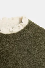 Jersey de punto color verde oliva con cuello redondo y mangas cortas. Presenta detalles de terminaciones en tejido pointelle de color crema en el cuello y los puños.