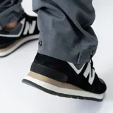 Pantalón utilitario gris con bajo ajustable a dos posiciones, bolsillos laterales y traseros.