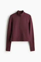 Campera deportiva corta color bordó con cierre frontal, cuello alto y mangas largas con abertura para el pulgar.