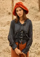 Camisa de satén color negro con acabado brillante, cuello en V, cierre frontal con botones de nácar y diseño ajustable con cordones laterales para fruncir.