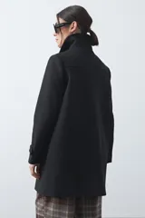 Tapado corto de paño color marrón, con diseño recto, cuello camisero y cierre frontal con broches metálicos. Cuenta con bolsillos frontales.