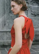 Top corto sin mangas de color rojo, con cuello redondo y diseño de espalda abierta con cierre de lazo. Cuenta con forro interior.
