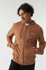 Campera con capucha de felpa color marrón, con estampado tipográfico en la espalda, bolsillo tipo cargo en la manga y puños elásticos.