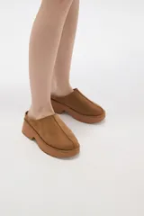 Zueco tipo mule de gamuza color camel, con plataforma de goma al tono y costura central decorativa.