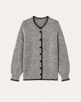 Cardigan de punto grueso en tono gris jaspeado, con cuello redondo y cierre frontal de botones. Presenta detalles de terminación en color negro con borde festoneado en el cuello, puños y ruedo, y mangas largas con puños ajustados.