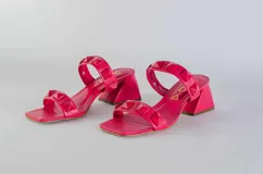 Sandalias rojas de tacón con dos tiras sobre el empeine adornadas con tachas piramidales. El tacón es ancho y de altura media.