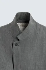 Blazer de corte regular confeccionada en tejido con lana, color gris. Presenta cuello con solapas de muesca, manga larga, bolsillos de vivo en el pecho y bolsillos de solapa en la cadera. Cuenta con cierre frontal de botones y aberturas en la espalda.