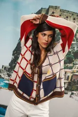 Cardigan oversized con diseño jacquard en tonos crema, rojo, azul y marrón. Tiene cuello en V, cierre con botones grandes, bolsillos frontales y etiqueta de cuero con logo Anthea en la parte trasera.