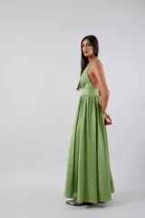 Vestido midi de color verde, con escote en V profundo, banda ancha bajo el busto y falda amplia con gran volumen. Presenta espalda baja y cierre invisible.