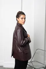 Blazer de cuero sintético negro con solapas clásicas, cierre frontal con botones y corte recto.