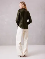 Camisa de satén color verde oliva, con cuello clásico, cierre frontal con botones metálicos y mangas largas con puños abotonados.